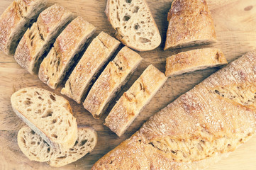 Sliced french baguette on wooden background. Toned image
