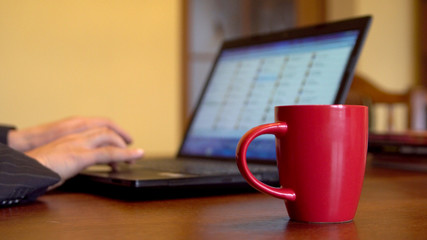 Fototapeta premium Businessman Working At Office, Desk With His Laptop And Drinking Coffee, Hands, Focus on red cup