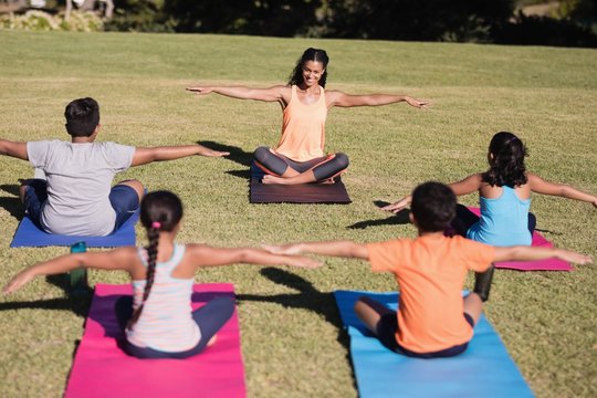 Happy trainer teaching stretching exercise to children