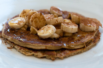 Banana and oat pancake with sliced bananas, cinnamon, and honey.