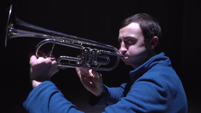 A musician plays the trumpet, isolated black background