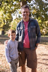 Portrait of happy man and boy standing in forest