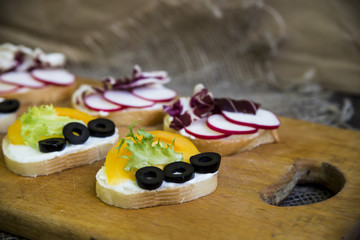 Obraz na płótnie Canvas Vegetarian vegetable bruschetta - with cheese, radish, yellow tomato, olives, cabbage and salad