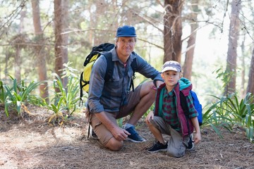 Portrait of father and son kneeling in forest