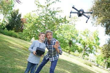 Father and son playing with flying drone in garden - obrazy, fototapety, plakaty