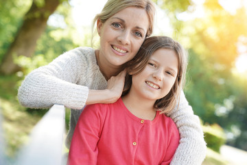 Portrait of mother and daughter sitting on bench outside