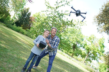 Father and son playing with flying drone in garden