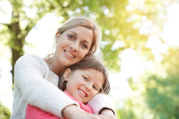 Portrait of mother and daughter sitting on bench outside