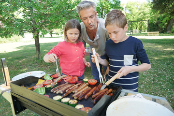 Naklejka na ściany i meble Father with kids preparing barbecue for family lunch
