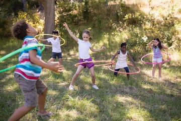 Cheerful friends playing with hula hoops at campsite