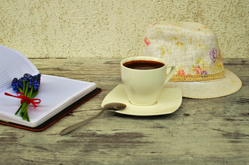 A cup of coffee and a spoon and a had on a light background.
