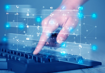 Hand pressing keyboard with high tech media icons