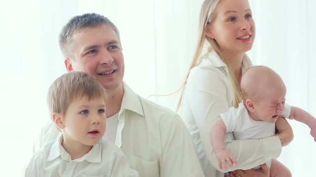 family with two sons on the background of a large window and smiling