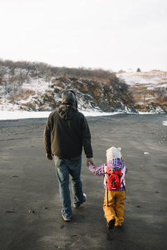 Father holding daughter's hand on beach