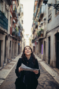 Enthusiastic traveler woman walking streets of european capital.Tourist in Lisbon,Portugal.Narrow, colorful,charming streets inviting curious woman tourist.Spending time and money traveling Europe