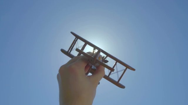 The hand play with a wood plane on the background of a bright sun