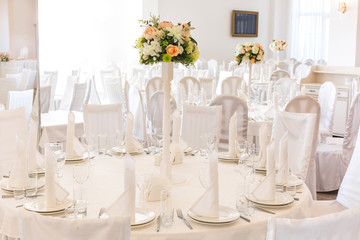 Festive table setting in classic style in a white restaurant interior, setout. Wedding table decor concept. Fine art. Expectation of guests.