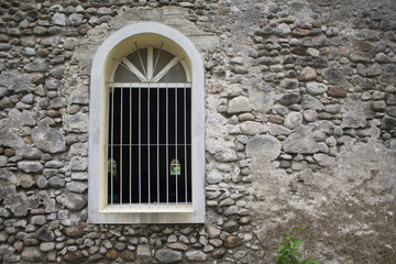 Fototapeta na wymiar White window in old grey stone wall. Old medieval architecture.