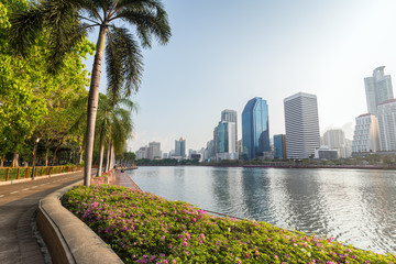 Jogging path, flowerbed and trees at the Benjakiti (Benjakitti) Park and modern skyscrapers in Bangkok, Thailand. © tuomaslehtinen