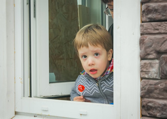 surprised child with candy, looking out the window into the street..