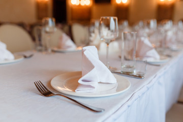 Beautifully elegant decorated table for holiday - wedding or valentine day with modern cutlery, bow, glass, closeup.