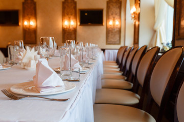 Beautifully elegant decorated table for holiday - wedding or valentine day with modern cutlery, bow, glass, closeup.