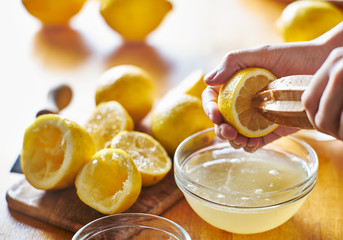 squeezing fresh lemon juice with wooden reamer into bowl - obrazy, fototapety, plakaty