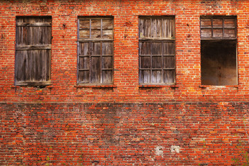 Wall from a red brick with wooden hammered windows. Wall of the old abandoned building. Textural background