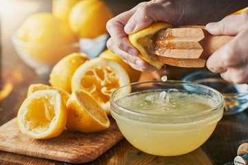 squeezing fresh lemon juice with wooden reamer into bowl - obrazy, fototapety, plakaty