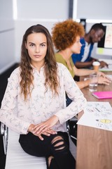 Portrait of businesswoman with colleagues at desk