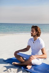 Fototapeta na wymiar Man performing yoga at beach