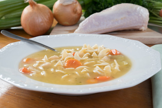 Bowl Of Chicken Noodle Soup On A Table With Ingredients