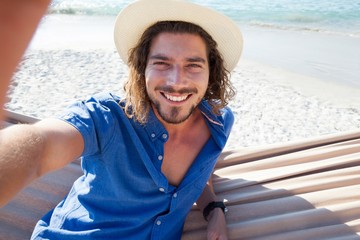 Fototapeta premium Man taking selfie while relaxing on hammock
