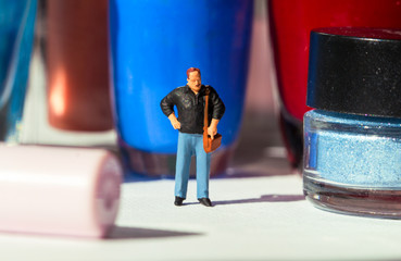 Man and women's nail polish. Husband miniature figure in decorative cosmetic land.