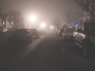 Parked cars in night time fog.