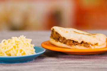 Traditional delicious arepas, shredded chicken avocado and cheddar cheese and shredded beef on wooden blackground