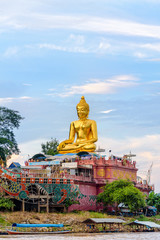 Beautiful golden buddha statue of Phra Buddha Nawa Lan Tue on the banks of the Mekong River at Golden Triangle Park (Sob Ruak) during the evening in Chiang Rai Province, Thailand