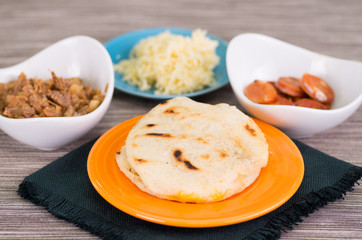 Close up of a traditional delicious arepas, shredded chicken avocado and cheddar cheese and shredded beef on wooden background