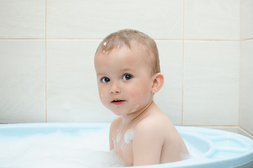 Happy baby boy taking a bath