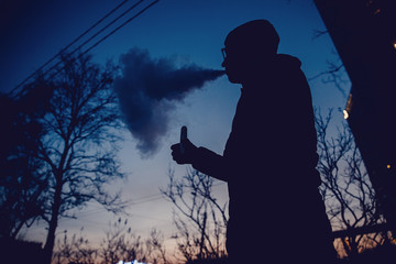 vaping man holding a mod device. cloud of vapor. Vape. high contrast and monochrome color tone.