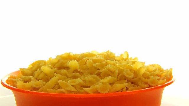 Close up pasta falling in the orange bowl rotating. Video food 360