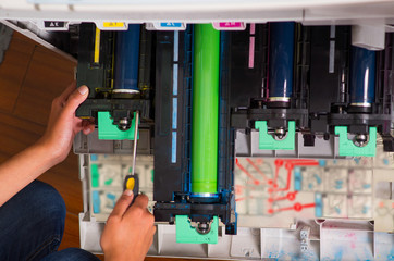 woman fixing a photocopier and smiling during maintenance using a screwdriver