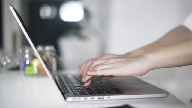 Close up of young woman s hands typing on a laptop keyboard. Locked down real time close up shot