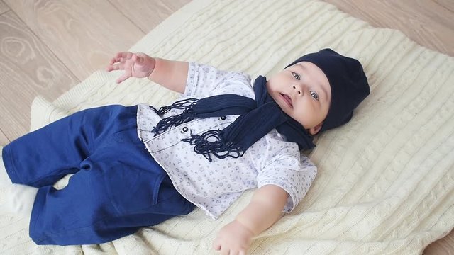 Pretty baby boy is lying on the white carpet