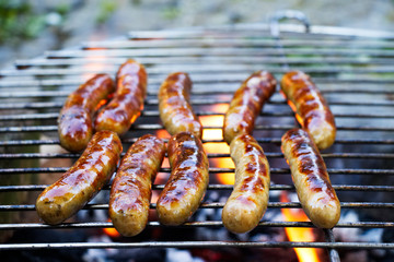 Grilling sausages on barbecue grill. BBQ in the garden. Bavarian sausages. 