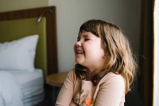 Little girl laughing in bedroom