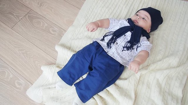 Pretty baby boy is lying on the white carpet