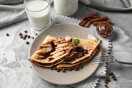 Plate with delicious pancakes and chocolate sauce on table