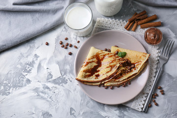 Plate with delicious pancakes and chocolate sauce on table