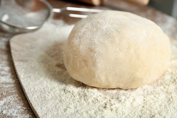 Board with raw dough on kitchen table, closeup